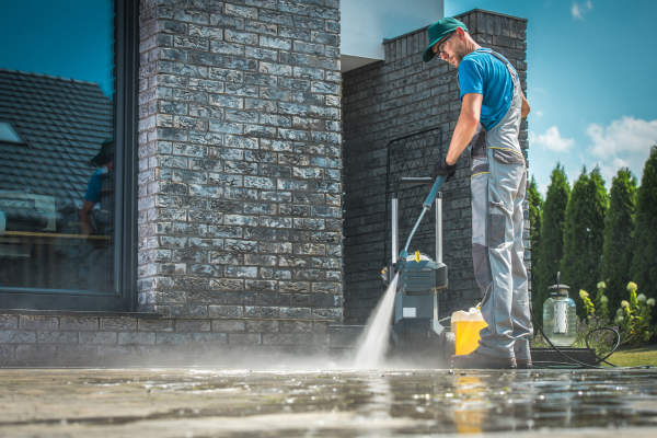 Guy in a blue shirt pressure washing a patio